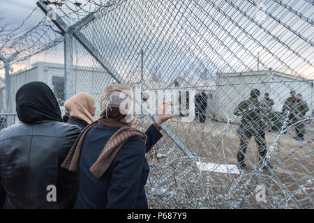 Les femmes regarder à travers les barbelés quand les migrants et les réfugiés d'attendre pour traverser la frontière entre la Grèce et la Macédoine au camp de réfugiés près de la fortune Banque D'Images