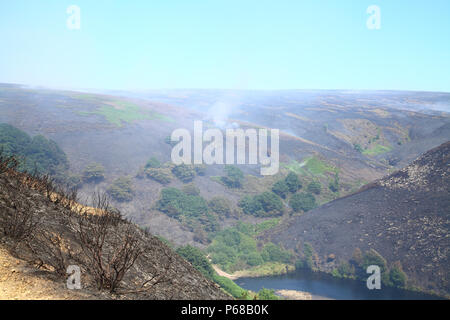 Tameside Moor, Manchester, UK - 28 juin 2018. Le Bellevue Moor wildfire continue à brûler le jeudi après-midi avec des pompiers à l'aide d'un godet d'hélicoptère pour essayer d'éteindre le feu et obtenir le feu. Crédit : Andrew Gardner/Alamy Live News Banque D'Images