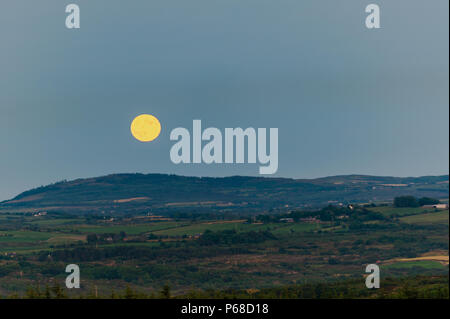 West Cork, Irlande. 28 Juin, 2018. Une spectaculaire pleine lune apparaît sur l'horizon sur West Cork après une journée de températures record. Certaines parties de l'Irlande a atteint le début de 30°'s Celsius. Les hautes températures devraient continuer demain, avant peut-être de céder la place à la pluie pendant la fin de semaine. Credit : Andy Gibson/Alamy Live News. Banque D'Images