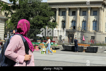 Berlin, Allemagne. 29 Juin, 2018. Une femme portant un foulard en passant devant la statue d'Alexander von Humboldt en face de l'entrée principale de l'Université d'Humboldt par la rue Unter den Linden. Le conseil d'administration de l'Université Humboldt est de décider de la création d'un institut de théologie de l'Islam, qui est controversée depuis le Comité consultatif académique de l'institut est affilié à trois associations déjà l'Islam conservateur, qui ont un droit de veto. Credit : Wolfgang Kumm/dpa/Alamy Live News Banque D'Images