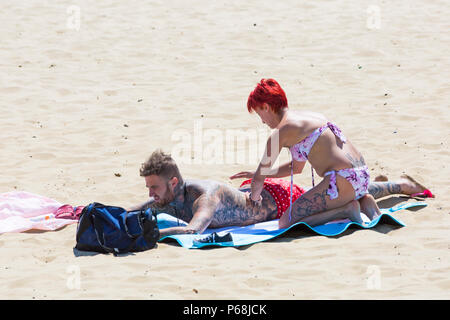 Bournemouth, Dorset, UK. 29 Juin, 2018. Météo France : sunseekers tête à la plages de Bournemouth sur un autre jour ensoleillé chaud avec un ciel bleu et soleil ininterrompue. Une légère brise rend la chaleur plus supportable. Woman rubbing lotion solaire crème sur nos partenaires retour. Credit : Carolyn Jenkins/Alamy Live News Banque D'Images