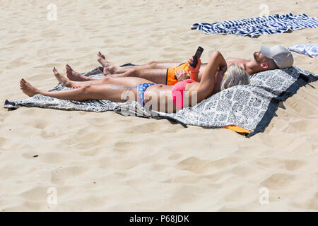 Bournemouth, Dorset, UK. 29 Juin, 2018. Météo France : sunseekers tête à la plages de Bournemouth sur un autre jour ensoleillé chaud avec un ciel bleu et soleil ininterrompue. Une légère brise rend la chaleur plus supportable. Couple de bronzer sur la plage. Credit : Carolyn Jenkins/Alamy Live News Banque D'Images