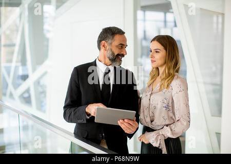 Les jeunes young regardez sur tablette numérique et discuter de nouveau projet in modern office Banque D'Images