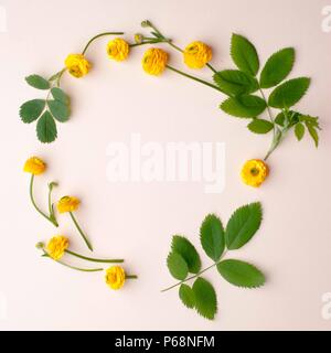 Composition de fleurs. Couronne constituée de diverses fleurs jaunes et vertes feuilles et branches sur fond jaune pastel. Mise à plat, vue du dessus, copiez l'espace, Banque D'Images