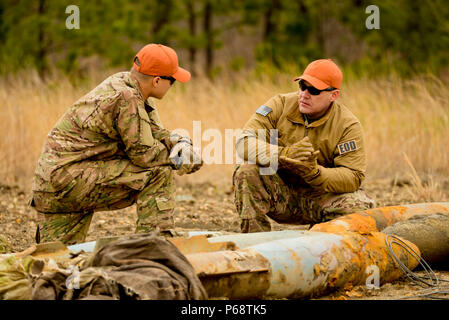 À partir de la droite, le sergent-chef de l'US Air Force. Raymond Wayne, des explosifs et munitions (NEM) Technicien à la New Jersey Air National Guard's 177e Escadre de chasse, et d'un membre de la 1re classe Michael Glisan, l'extension de la technologie avec le 87e Escadron de génie civil, Joint Base McGuire-Dix-Lakehurst, discuter par-le-livre techniques d'empilage triple C-4 sur les explosifs utilisés bombes pratique pour les rendre sécuritaires pour le recyclage à Warren Grove en gamme Ocean Comté, N.J. le 29 avril 2016. Les membres de NEM, les ingénieurs civils et la gamme crew ont travaillé ensemble pendant la semaine annuelle à l'EOD 'gamme' pour effectuer le nettoyage et la plage Banque D'Images