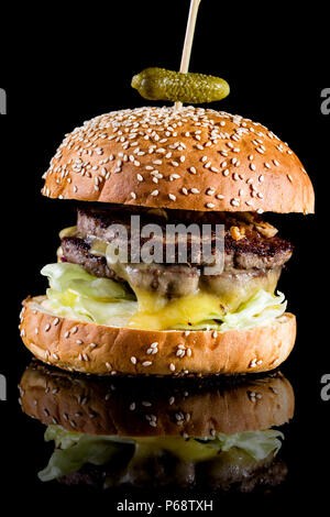 Bouche-arrosage burger garni d'oignons frits, mûri le cheddar et le ketchup avec réflexion isolé sur fond noir Banque D'Images