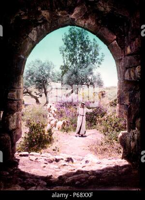 Photographie couleur d'un jeune berger arabe vu à travers une arche en Palestine. Datée 1910 Banque D'Images