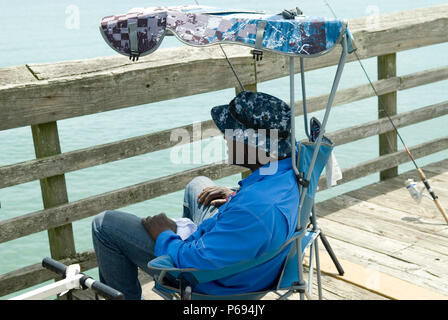 L'homme se détend dans la présidence sur une jetée à Myrtle Beach State Park, SC, USA. Banque D'Images