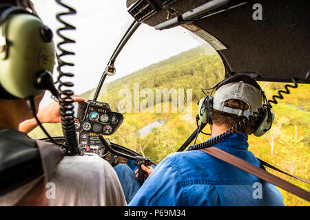 Jock au bâton de contrôle de son hélicoptère Robinson R44 Raven dans le territoire du Nord, en Australie Banque D'Images