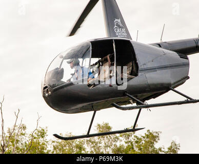 Jock au bâton de contrôle de son hélicoptère Robinson R44 Raven dans le territoire du Nord, en Australie Banque D'Images