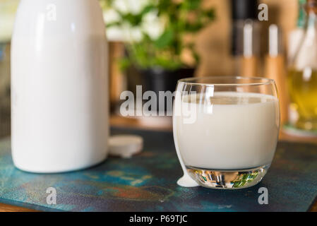 Vue rapprochée de kéfir frais probiotik verre en verre clair et blanc bouteille sur la table de cuisine. Banque D'Images