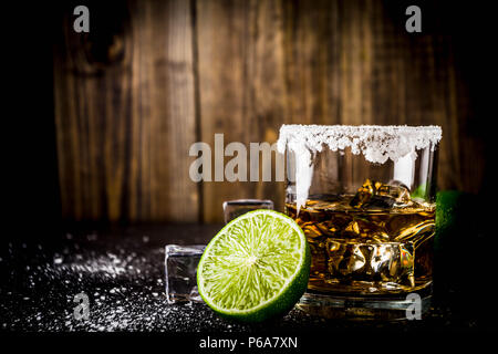 Deux verres de tequila sur fond sombre, avec des cubes de glace, de sel et de chaux copy space Banque D'Images