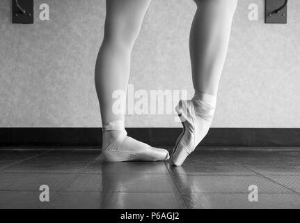 Version noir et blanc de ballerine réchauffe ses pieds dans ses chaussures de pointe pour le cours Banque D'Images