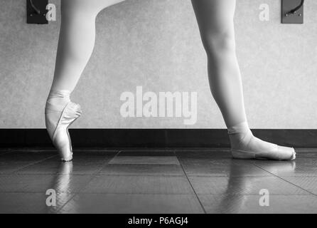 Version noir et blanc de ballerine dans le cours de l'échauffement il pointe des chaussures, des chaussons de ballet à la barre Banque D'Images