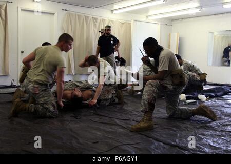 Soldats affectés au 4e Groupe de soutien de l'information militaire préparer un groupe Gryphon rôle-player de solutions de sécurité pour l'évacuation médicale d'urgence alors que l'effectif du cours évaluer leur performance au cours d'une formation médicale lane, le 4 mai 2016. Le lane stands un petit contingent contre une force écrasante supériorité avec le feu. L'équipe doit se rendre à un point d'extraction tout en fournissant de l'aide médicale aux blessés qu'ils ont subies en cours de route. Soldats entraînés sur recherche avancée, tir au pistolet, conduite d'évitement et techniques de premiers secours au cours de la cours d'une semaine à l'Entraînement au Combat de Fort Bragg Cen Banque D'Images