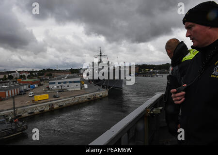 180621-N-FP878-029 Kiel, Allemagne (21 juin 2018) Le Cmdr. Patrick Murphey, commandant de la classe Arleigh Burke destroyer lance-missiles USS Bainbridge (DDG 96), des montres à partir de l'aileron de passerelle que le navire quitte Kiel, Allemagne, suite à un service au port, le 21 juin, 2018. Bainbridge, homeported à Naval Station Norfolk, mène des opérations navales dans la sixième flotte américaine zone d'opérations à l'appui de la sécurité nationale des États-Unis en Europe et en Afrique. (U.S. Photo par marine Spécialiste de la communication de masse 1re classe Theron J. Godbold/libérés) Banque D'Images