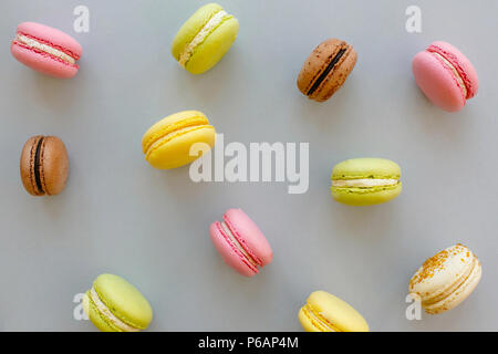 Macarons colorés sur papier gris pastel à la mode, télévision jeter. délicieux rose, jaune, vert et brun chocolat macarons. pour partie. La photographie culinaire. yummy b Banque D'Images