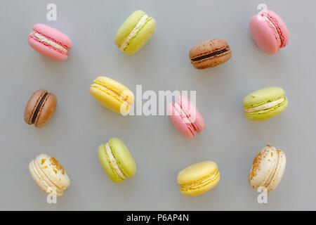 La photographie alimentaire instagram macarons colorés. sur du papier gris pastel à la mode, télévision jeter. délicieux rose, jaune, vert et brun chocolat macarons. pour la partie Banque D'Images