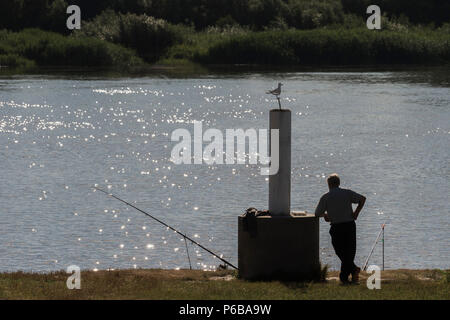 Pêcheur sur la rivière. L'homme en chaise pliante sur la banque s'attend à ce que le poisson. Banque D'Images