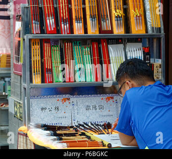 L'homme à l'aide de brosse pour créer écrire le chinois Calligraphie texte au marché d'antiquités de Panjiayuan, Beijing Banque D'Images
