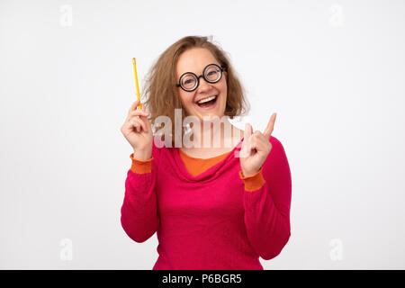 Closeup portrait femme européenne drôle de penser comme elle a une bonne idée isolé sur fond de mur gris. Elle est en cercle étrange lunettes. Idée, busi Banque D'Images