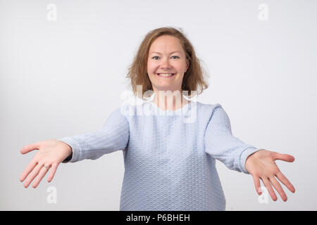 Bienvenue ou bien de vous rencontrer concept. Femme européenne en pull bleu avec poignée de mains tendues. Elle veut embrasser son amis. Une expression de l'émotion Banque D'Images