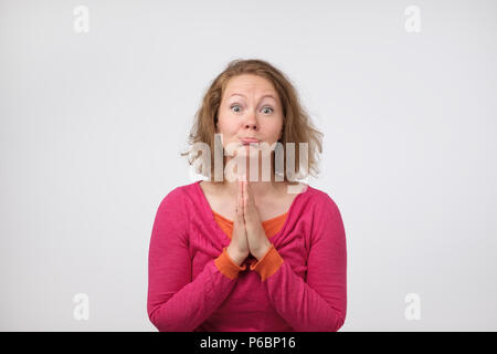 Veuillez me pardonner. Frustrés d'âge moyen triste femme européenne appuyant sur paumes ensemble, avoir l'expression du visage triste, suppliant, mendicité copain f Banque D'Images