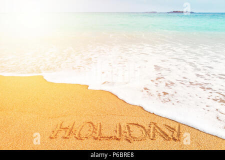Belle plage ensoleillée par la mer bleue. Maison de vacances "Word" écrit sur le sable Banque D'Images