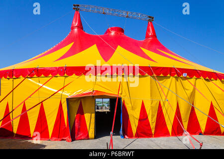 Tente de cirque ou big top design en rouge et jaune se détachant sur un ciel bleu clair. Banque D'Images