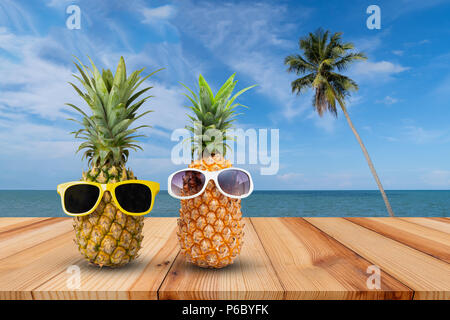 L'ananas sur table en bois dans un paysage tropical, la mode hipster pineapple, lumineux couleur d'été, des fruits tropicaux avec des lunettes de soleil, couple d'attractiv Banque D'Images