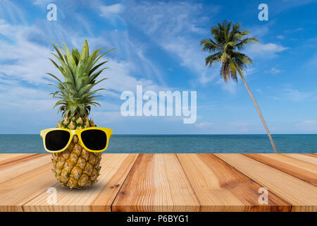 L'ananas sur table en bois dans un paysage tropical, la mode hipster pineapple, lumineux couleur d'été, des fruits tropicaux avec des lunettes de soleil, couple d'attractiv Banque D'Images