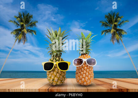 L'ananas sur table en bois dans un paysage tropical, la mode hipster pineapple, lumineux couleur d'été, des fruits tropicaux avec des lunettes de soleil, couple d'attractiv Banque D'Images