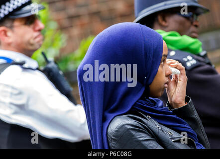 Le premier anniversaire de la tour de 24 étages de Grenfell bloc appartements de logement public qui a fait l'incendie 72 vit. Jeune femme wipes larmes pendant le public service commémoratif, South Kensington, Londres, Royaume-Uni, le 14 juin 2018. Banque D'Images