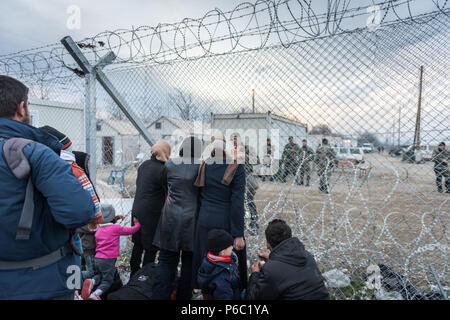 Les femmes regarder à travers les barbelés quand les migrants et les réfugiés d'attendre pour traverser la frontière entre la Grèce et la Macédoine au camp de réfugiés près de la fortune Banque D'Images