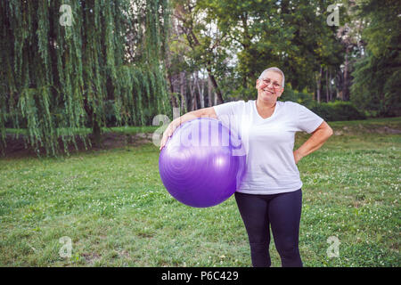 Smiling senior femme avec des boules de forme physique dans l'exercice et du parc Banque D'Images