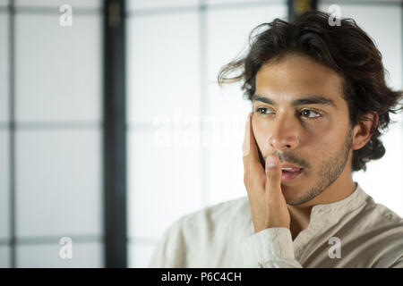 Close Up of Young Man de toucher sa joue Banque D'Images