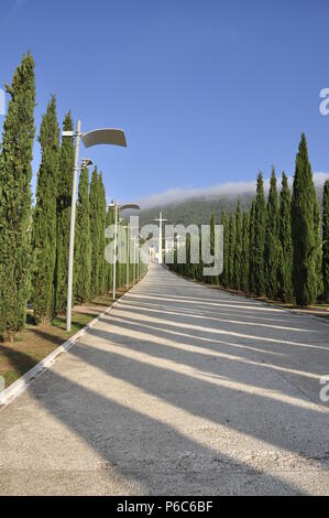 Entre les arbres et les lampes de la rue menant à une croix blanche et le sanctuaire de Padre Pio de Pietrelcina Banque D'Images