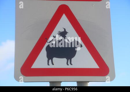 Un roadsie signe qui a été adapté par un artiste graffit de montrer un mouton avec une sorcière et chat noir sur le dos des moutons. Banque D'Images