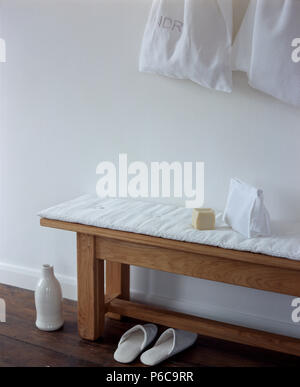Sac à linge en coton blanc au-dessus d'un simple banc en bois avec un coussin blanc Banque D'Images