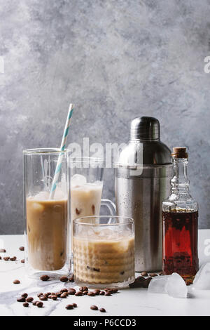 Cocktail café glacé frappe) avec des cubes de glace et de la crème dans des verres avec silver shaker, bouteille de rhum, les grains de café autour de marbre blanc sur ta Banque D'Images