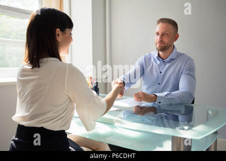 Smiling Young Businessman Shaking Hand avec Candidate sur 24 sur le lieu de travail Banque D'Images