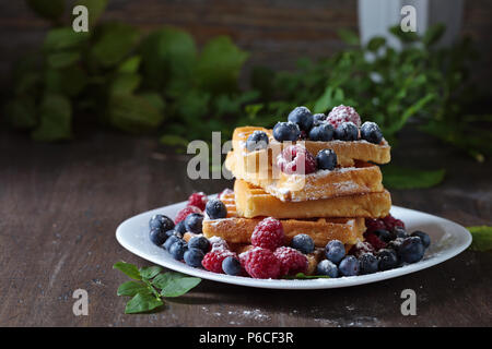 Gaufres sucrées délicieux à la framboise et du bleuet sur une vieille table en bois . Banque D'Images