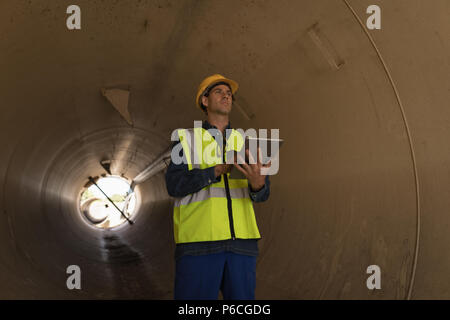 Male worker using digital tablet tout en examinant un tunnel en béton Banque D'Images