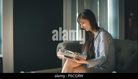 Woman Reading magazine dans la salle de séjour Banque D'Images