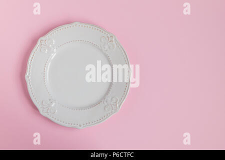 Rustique blanc sur plaque rose clair pastel arrière-plan. Plaque sur le côté gauche du châssis. Vue d'en haut. Banque D'Images