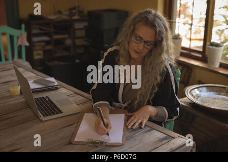 Mature Woman sitting on chair et écrit sur papier Banque D'Images