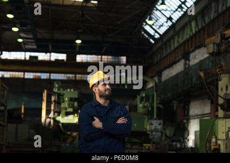 Technicien réfléchi standing with arms crossed Banque D'Images