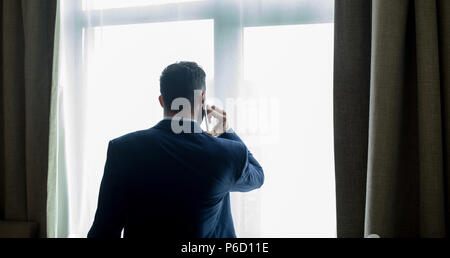 Businessman talking on mobile phone in hotel room Banque D'Images