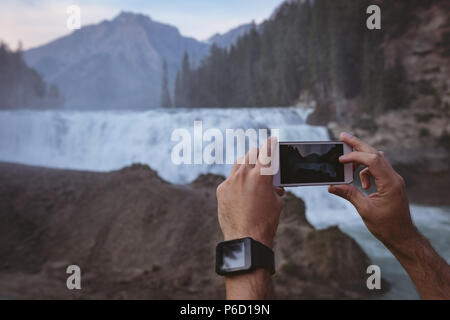 Man taking photo de cascade avec un téléphone mobile Banque D'Images