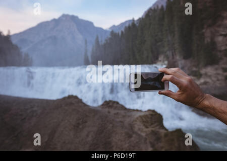 Man taking photo de cascade avec un téléphone mobile Banque D'Images